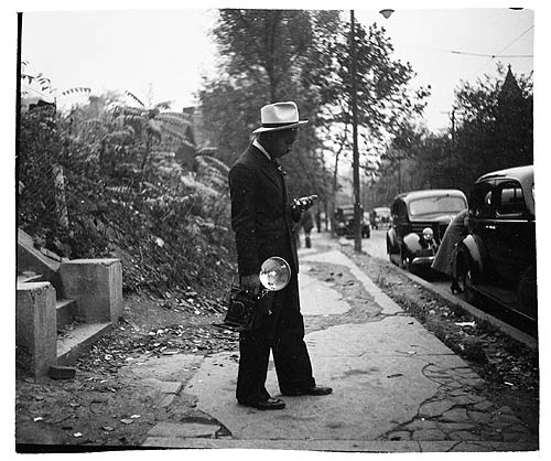 Teenie Harris holding camera and standing on sidewalk c 1938