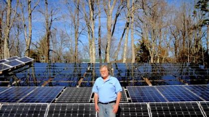 John Prusa, 57, director of innovation and technology for New Vision Renewable Energy, stands with the solar panels that have helped his Philippi, W.Va., home run on renewable energy.