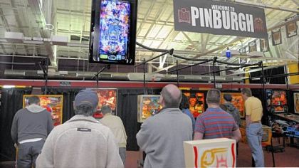Visitors watch a video screen from a camera above one of the pinball machines. The players are practicing for the Professional & Amateur Pinball Association Pinburgh tournament in Scott. The weekend-long event is one of many regional tournaments being held throughout the country. The national championship will be held in August.