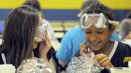 Maranda Phillips, 10, and Maura Bryant, 9, fourth-graders at Cornell Elementary School in Coraopolis, take part in the LabRatz science program in which they were learning about the surface tension of water.