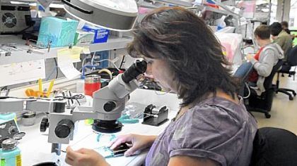 Chris Couts uses a microscope to make tiny welds on a defibrillator circuit board at Zoll Medical in the RIDC Park in O'Hara.