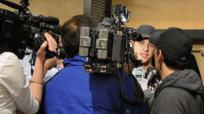 Sidney Crosby is surrounded by media at his locker as the team packs their equipment.