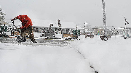 A man shovels wet, heavy snow in Windber, Somerset County, today as a spring storm dumped snow and rain across the northeast.