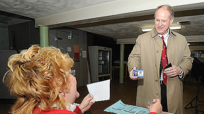 Congressman Mark Critz shows his photo ID to Kelly Swanson, minority inspector at precinct 17-2, as he prepares to vote today in Johnstown, Cambria County.