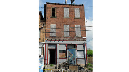 Contractors Lou Kavulic, left, and Jeremy Milbee work on the roof at the August Wilson home in the Hill District.