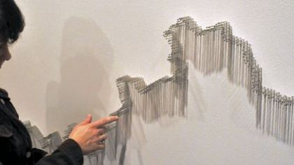 Art handler Chantal Bernicky checks for uniform pin height for Maya Lin's installation "Pin River -- Ohio (Allegheny and Monongahela)," being installed at Carnegie Museum of Art.