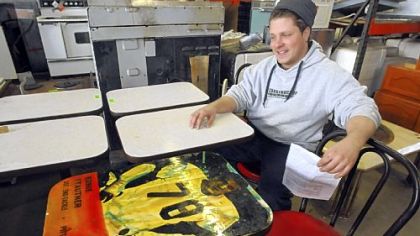 Construction Junction's Ben Lloyd with tables removed from a Downtown fast food restaurant. Some of the tabletops were decorated with pictures of famous Steelers players; the only decorated table remaining features Ernie Stautner.