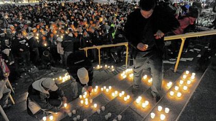 Students light candles on the steps of Old Main Sunday night in honor of Joe Paterno.