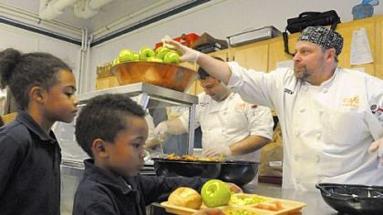 Shawn Carlson and Drew Danver, right, from Cafe Phipps serve the White House's suggested school lunch Wednesday to Peyton Walker and Jacy Willis, left, at The Environmental Charter School in Regent Square.