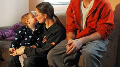 Melissa Watkins kisses her 17-month-old daughter, Steffany, while sitting with her fiance, Trevor Miles, for a television interview at their home in Beltzhoover on Friday.  Ms. Watkins is one of four women who has told police that Officer Adam Skweres offered to grant them legal favors in exchange for sexual acts.