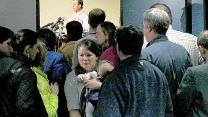 Kate Chase carries her 8-week-old daughter, Eva, from an over-capacity room where former Pennsylvania Sen. Rick Santorum, background, was speaking Friday in Keene, N.H.