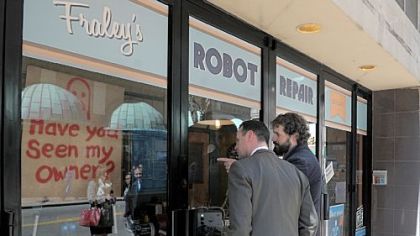 Mayor Luke Ravenstahl looks into the storefront window of Fraley's Robot Repair with artist Toby Fraley.
