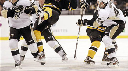 Boston Bruins' Daniel Paille is tripped up between the Penguins' Tyler Kennedy, left and Brooks Orpik (44) during the second period of this afternoon's game in Boston.
