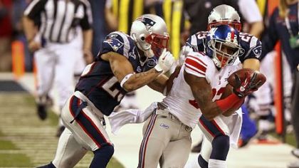 Mario Manningham #82 of the New York Giants makes a catch on the sidelines against Patrick Chung #25 and Sterling Moore #29 of the New England Patriots for a gain of 39 yards in the fourth quarter.