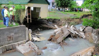 Carnegie Public Works workers contemplate the mass of debris littering the channel of Campbell's Run behind the homes on Lexington Court in June 2010. Heavy rains sent the creek into the street, filling basements and collapsing concrete retaining walls.
