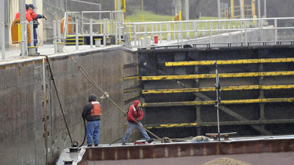 In a driving rainstorm, deckhands on the Consol Energy towboat Aliquippa fasten their barges inside Lock 4 at Charleroi on the Monongahela River and head for Monessen with two jumbo barges of sand.