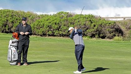Tiger Woods hits from the fairway up to the 10th green of the Monterey Peninsula Country Club shore course as his caddie, Joe LaCava, left, looks on during a practice round Wednesday at the Pebble Beach National Pro-Am golf tournament in Pebble Beach, Calif.