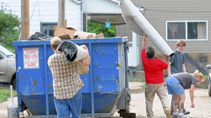 Carnegie residents parade to dumpsters with goods from their flood-damaged basements.