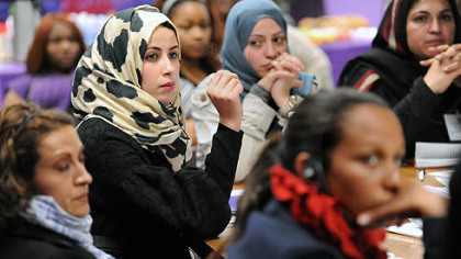 Hana Elhebshi of Libya, center in the printed scarf, asks a question during a talk and reception for awardees at Gwen's Girls in Point Breeze.