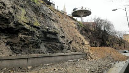 A Pittsburgh public works crew uses an excavator to push part of the hillside down onto McArdle Roadway on Thursday. Grandview Avenue is closed, above the site, due to equipment working above McArdle.