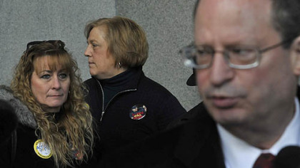 As attorney Michael P. Malakoff, right, speaks about the need for restraint in foreclosing on people's homes because of a failure by Pennsylvania banks to properly file paperwork, Kathy Todd, left, of Lincoln Place, whose foreclosure was stopped, listens during at a news conference on the portico of the City-County Building on Thursday. Standing in the background is Cathy Holler, a community activist from Ambridge.