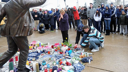 Penn State alumni Michael Ward, 24, center, and Chris Berberich, 25, pay tribute to the late Joe Paterno at his statue outside Beaver Stadium in State College.