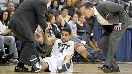 Pitt athletic trainer Tony Salesi, left, and coach Jamie Dixon assist John Johnson after he was slow to get up against Cincinnati in the first half Sunday night at Petersen Events Center.