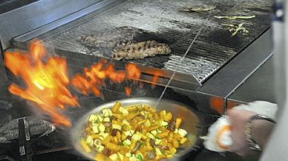 Executive chef Kevin Hermann hits a pan of sweet potato gnocchi with white wine as he cooks it with dates, pancetta and apple.