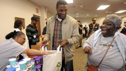 Steelers' defensive back Ryan Mundy helps Nan Strong (right) gather her Thanksgiving meal fixings at the Dignity & Respect Campaign to  distribute Thanksgiving foods at the Rankin Christian Center in November. Mundy was joined by teammate Charlie Batch and other volunteers to distribute turkey, yams, corn, green beans, cranberry sauce, stuffing and dessert.