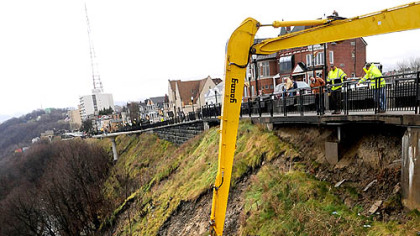 A City of Pittsburgh Public Works crew pushes part of the hillside down onto McArdle Roadway. Grandview Avenue in Mount Washington also is closed during the work.