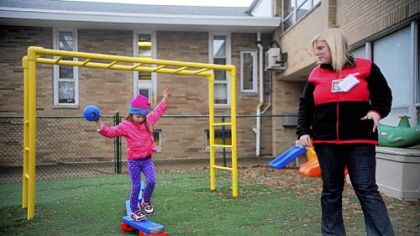 A 4-year-old walks along a balance beam while being supervised by Taryn Revak during playtime at ABC's for Children day care in Scott.