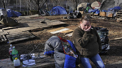 A member of the Occupy Pittsburgh movement sits on a bench with her belongings as the encampment on BNY Mellon's property is dismantled.