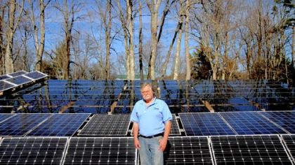 John Prusa, 57, director of innovation and technology for New Vision Renewable Energy, stands with the solar panels that have helped his Philippi, W.Va., home run on renewable energy.