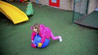 Another 4-year-old child rolls over an exercise ball. The day care center sets aside time for physical play every two hours.