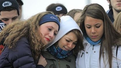 From left, Annelise Gaus of Wexford, Meredith Moore of Doylestown, Pa., and Tanya Cuadra of Rockville, Md., comfort each other Sunday at a memorial for coach Joe Paterno at his statue outside Beaver Stadium. The young women, who sung the alma mater at the memorial, are part of the Penn State Singing Lions.