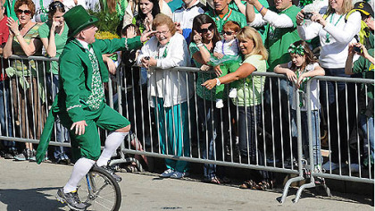 A unicyclist entertains the crowd along the Boulevard of the Allies during the St. Patrick's Day Parade Downtown today.