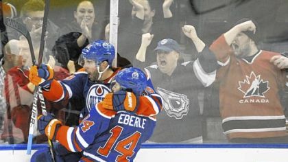 Edmonton Oilers' Jordan Eberle, right, congratulates Sam Gagner on his goal against the Blackhawks in the third period Thursday in Edmonton, Alberta. Gagner ended the game with four goals and four assists.