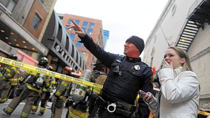 Resident Amanda Belhumeur, right, talks to a police officer Thursday as firefighters respond to a fire on the ninth floor of the Roosevelt Arms building along Penn Avenue, Downtown. An unconscious resident died after being rescued.