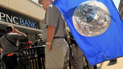 John Haer of the East End holds a flag with the Earth on it as part of a rally with the Earth Quaker Action Team. The group was protesting PNC's financing of mountaintop removal mining.