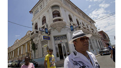 Folks walk past Norma Arias Puente's Casa Catedral on the square in Santiago de Cuba.