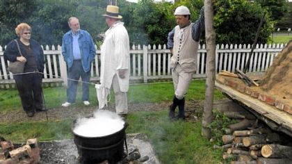 Visitors Nelson Cappy and his wife Nancy Cappy talk with volunteers Rob Windhorst and Dan Ragaller about the process of doing laundry in colonial days at Woodville Plantation.