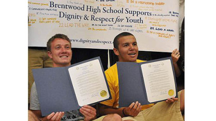 Brentwood's Sean O'Brien, left, and Monessen's Justice Rawlins, right, pose with proclamations presented to both schools by Brentwood's mayor to mark the schools' efforts Wednesday to combat the conflicts of this past winter.
