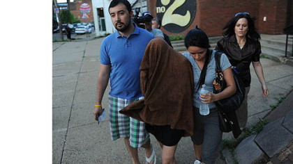 Draped in a towel to conceal her face, Claudia Manrique, 26, of Silver Spring, Md., leaves the Zone 2 police station in the Hill District after hours of questioning on Wednesday.