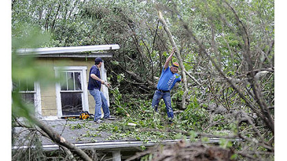 Barry Hines, left, of Mihalko General Construction and Denny Bloom of Johnstown work Saturday on clearing fallen trees from the home of Dorothy Felbaum along Route 711 in Ligonier after an EF1 tornado swept through the area Friday.