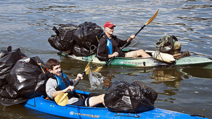 Evan Chernicky, left, and Steve Chernick paddle kayaks full of trash up the Allegheny River last September.