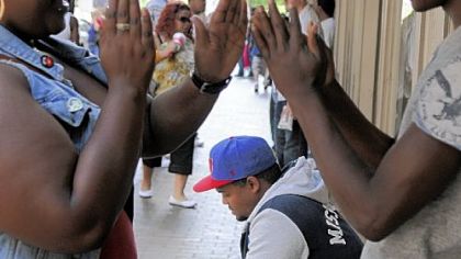 Brandon Binion, 26, center, of the North Side sends a text message while Sydney Rini, 19, left, and Michael Worthy, 18, right, both of Brighton Heights, play a game while waiting for the release of the Nike Air Yeezy 2 outside Social Status on Liberty Avenue, Downtown, on Friday.