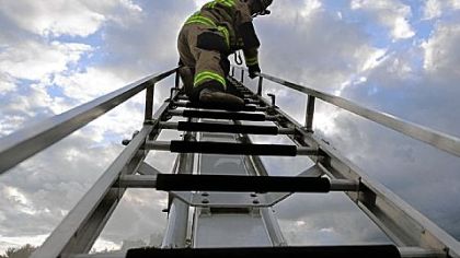 Lt. Don Knouse, a volunteer fire fighter from Moon, scrambles up the ladder of a "squirt truck" during a pump practice drill at the station in Moon.