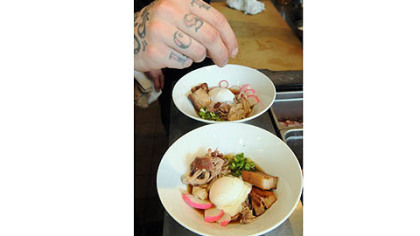 Kevin Rubis puts the final garnish on the Ramen noodle soup at the Salt of the Earth Restaurant.