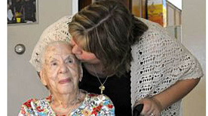 Frances Elliott, 100, gets a kiss from granddaughter Chrissy Corcoran at Mrs. Elliott's McKees Rocks home Friday.