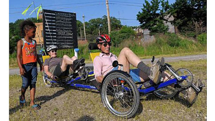Felicia Williams, 6, of Hazelwood watches as Mary Shaw and her husband, Roy Weil, of Squirrel Hill pull away in their tandem recumbent tricycle to ride home Friday.